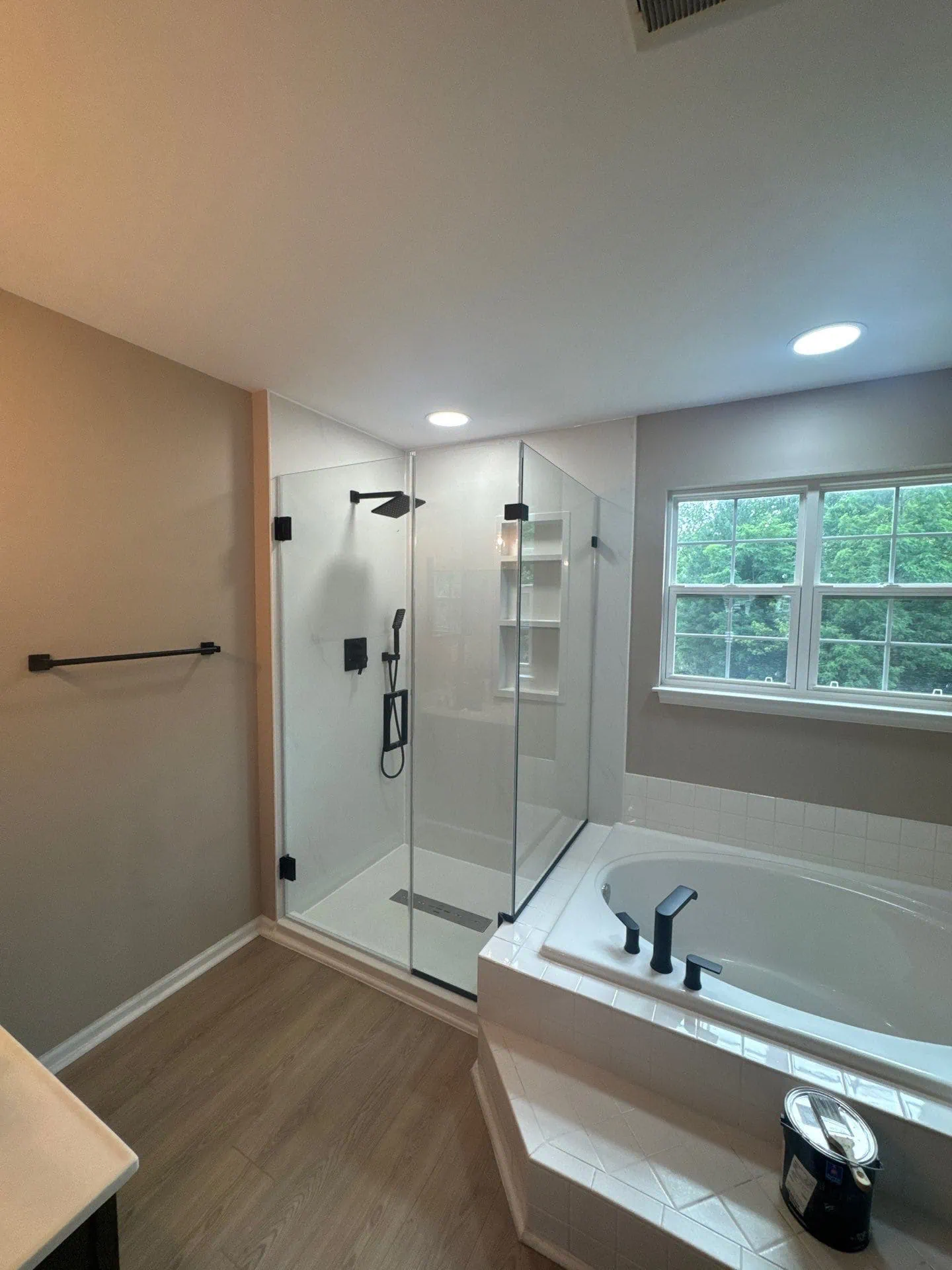 Bathroom remodel in Fort Washington MD with a modern walk-in shower, marble-look walls, black fixtures, and glass enclosure